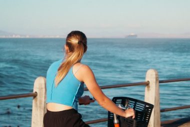 Woman riding a bike by the sea.
